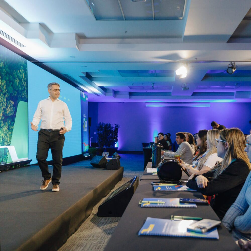 Renato da Silveira em palestra no palco para plateia do setor de combustíveis