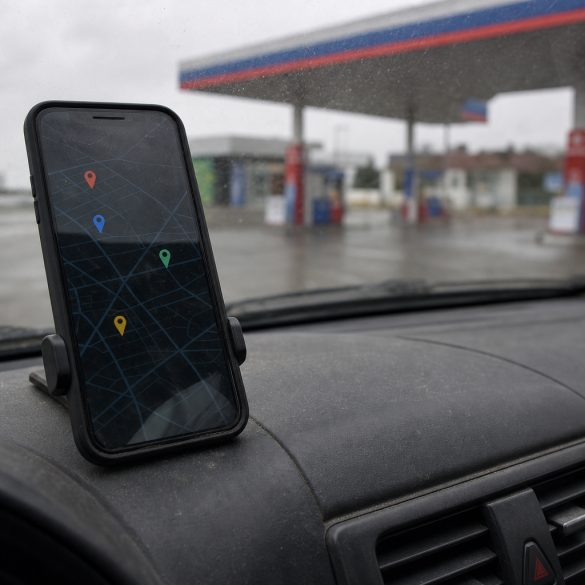 Celular em uso mostrando um mapa genérico, com um posto de combustível desfocado ao fundo