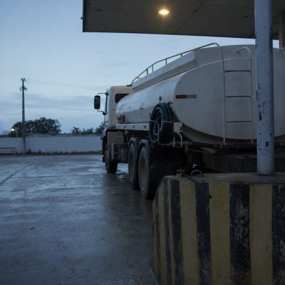 Caminhão-tanque parado na área de carregamento de um posto ao amanhecer