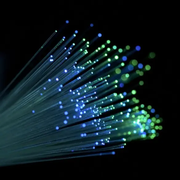 Feixe de fibras ópticas iluminadas em azul e verde, em close, representando fluxo de dados